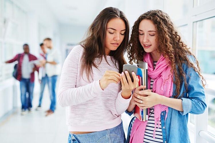 Zwei junge Frauen recherchieren über das Handy im Internet