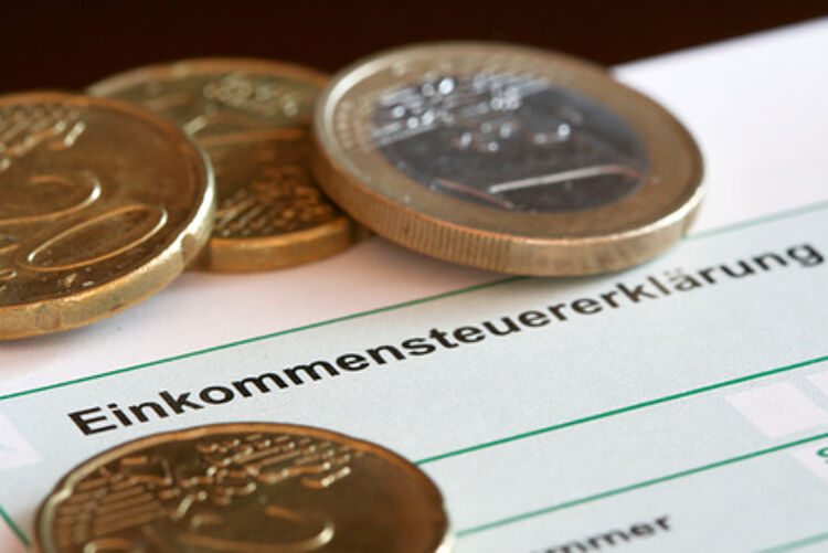 Euromünzen liegen auf einer Einkommensteuererklärung Euromünzen liegen auf einer Einkommensteuererklärung